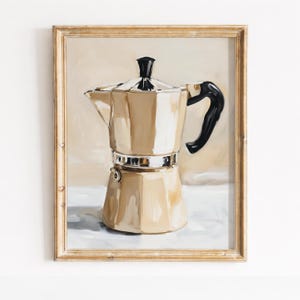 Pode incluir: Obra de arte emoldurada com uma cafeteira em tons de bege e dourado, com uma alça e tampa pretas. A pintura tem uma estética vintage, em um fundo neutro, e está contida em uma moldura dourada.