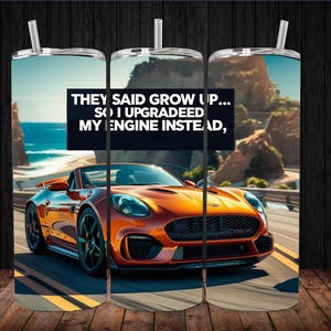 May include: A stainless steel tumbler with a straw features an orange sports car on a coastal road. The text on the tumbler reads: "They said grow up... so I upgraded my engine instead."