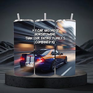 Puede incluir: Un vaso de acero inoxidable con un diseño de coche. El vaso presenta un coche deportivo azul y naranja que corre a toda velocidad por una carretera, con el texto "MY CAR HAS MORE HORSEPOWER THAN YOUR ENTIRE FAMILY'S COMBINED IQ."