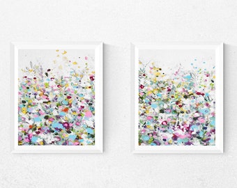 May include: Two framed abstract paintings with a white background and colorful splatter paint in shades of pink, blue, green, yellow, and purple.