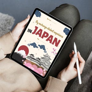Peut inclure: Une tablette numérique affichant un graphisme sur le thème du voyage avec le texte "My exchange student experience IN JAPAN". Le design comprend des illustrations du Mont Fuji, d'un château japonais, de nuages et de fleurs de cerisier. Un stylet blanc est tenu à proximité.