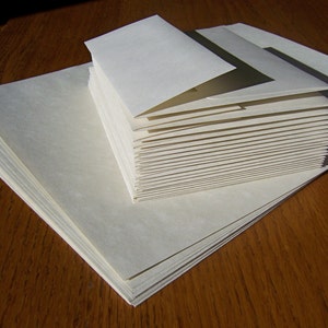 May include: A stack of white envelopes, with the top envelope folded over to reveal the stack of envelopes underneath.