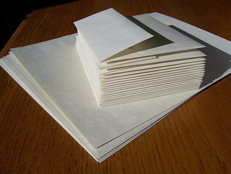 May include: A stack of white envelopes, with the top envelope folded over to reveal the stack of envelopes underneath.