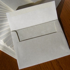 May include: A stack of white envelopes with a single envelope on top, open and ready to be used.