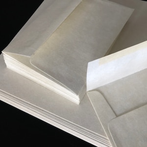 May include: A stack of white envelopes with a single envelope partially open, revealing a white adhesive strip.
