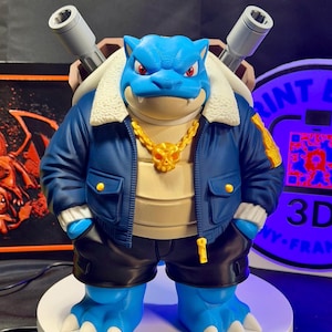 May include: A blue bipedal creature figurine with red eyes, wearing a dark blue bomber jacket over a cream-colored shirt, black shorts, and a gold skull necklace. Two large gray cannons protrude from its back, and it has white claws on its feet.