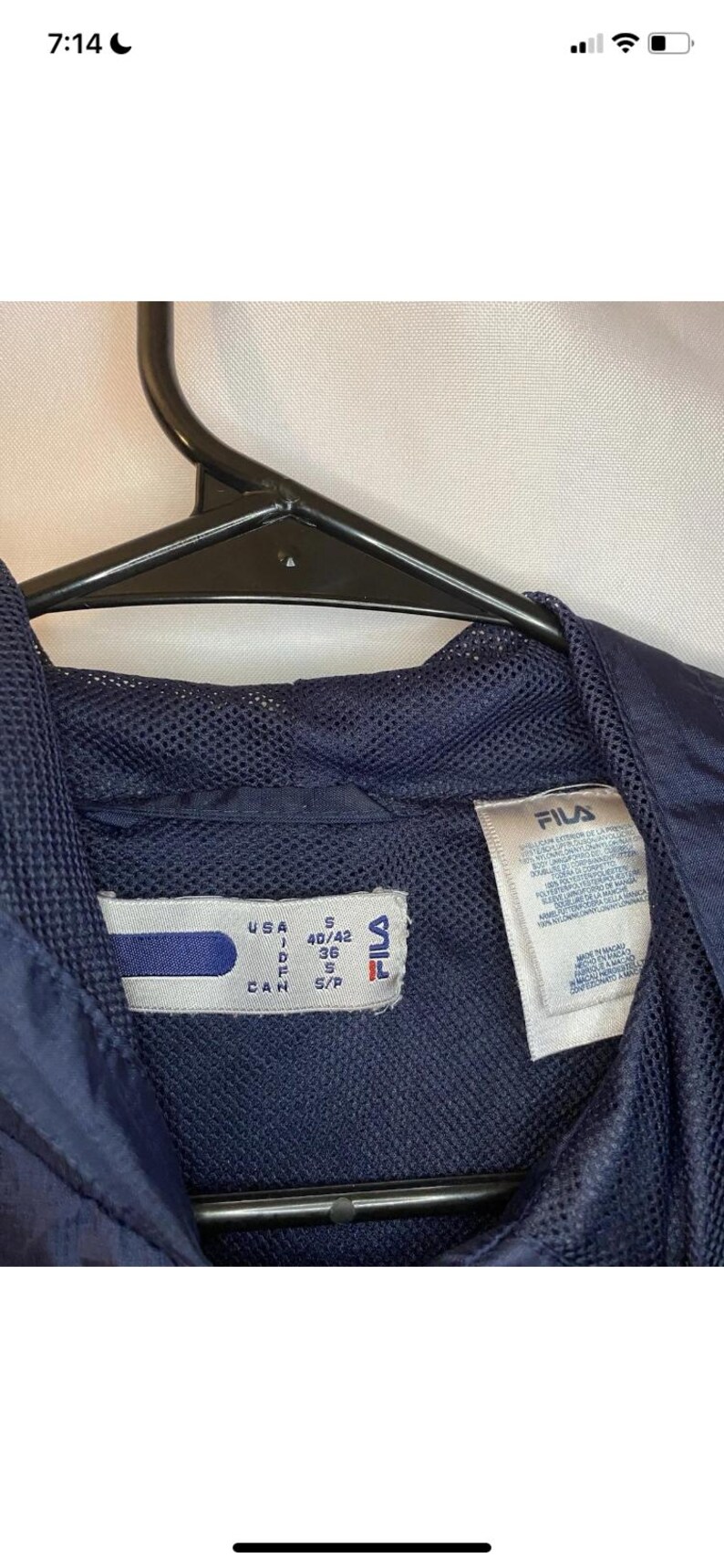 May include: Navy blue Fila jacket with a mesh lining. The tag indicates a size S for the USA, with measurements of 40/42. The jacket is hanging on a black hanger.