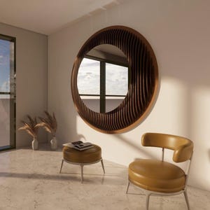 Puede incluir: Un espejo grande y redondo con un marco de madera estriado cuelga de una pared blanca. El espejo refleja una ventana con un diseño en forma de cruz. Un pequeño otomán redondo y una silla con asiento amarillo están frente al espejo.