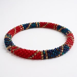 May include: A beaded bracelet with a spiral design. The bracelet features red, blue, and gold beads. The bracelet is approximately 2.5 inches in diameter.