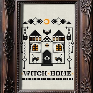 Pode incluir: Um padrão de ponto cruz numa moldura ornamentada castanho-escura com uma casa preta de janelas cor de laranja, dois gatos pretos, um morcego e uma lua crescente. O texto WITCH HOME está bordado a preto na parte inferior com bordas.