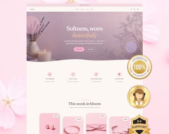 May include: A website template design featuring a soft lavender and pink color palette. The header displays the text 'LAUNCH YOUR STORE IN 1 DAY' and 'Softness, worn beautifully'. The page includes product listings, icons for shipping, and three gold circular badges.