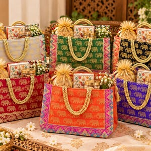 May include: Six rectangular fabric gift bags in light blue, green, black, red, orange, and purple, each featuring a repeating gold elephant pattern, gold braided handles, and filled with small gift boxes, jars, and organza pouches.