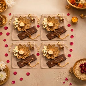 May include: Four sets of gold-colored metal lotus-shaped candle holders, each placed on a beige fabric drawstring pouch. Each set includes a small brass bell and a rectangular wooden tag with Hindi text, tied with a yellow cord and a lit tea light.