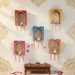 May include: Five colorful wall-mounted decorative pieces with arched window designs. Each piece features a different color frame, a lattice-like interior, and a small candle. The pieces are adorned with floral accents and hanging tassels.