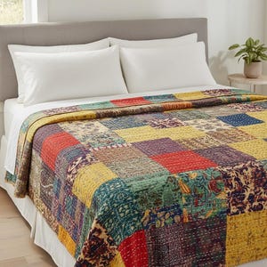 May include: A patchwork quilt with a variety of colors and patterns, including red, yellow, green, and blue squares. The quilt is on a bed with white sheets and pillows. The quilt has a textured appearance and is likely made of fabric.
