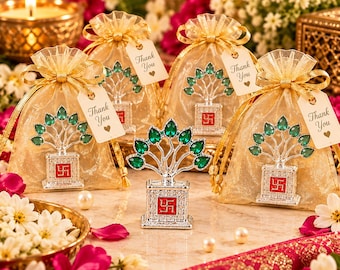 May include: Four silver-toned tree-shaped ornaments with green teardrop-shaped accents and a red square base featuring a swastika symbol. Three ornaments are inside gold organza drawstring bags with Thank You tags attached by gold ribbons.