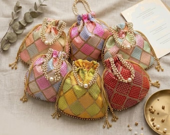 May include: A collection of colorful potli bags with a checkered pattern. Each bag features a drawstring closure, pearl accents, and a beaded handle. The bags are in various colors, including pink, yellow, and red. The text "THE ROYAL POTLI BAG COLLECTION" is at the bottom.
