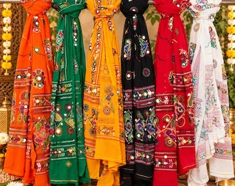 May include: Six rectangular scarves in orange, green, yellow, black, red, and white, each featuring intricate multi-colored embroidery and small circular mirrors arranged in horizontal bands and floral patterns, hanging side by side.