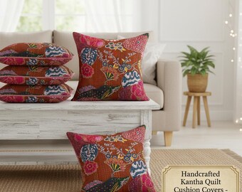 May include: A set of five handcrafted Kantha quilt cushion covers. The covers feature a warm brown background with colorful floral and abstract patterns in pink, blue, and green. The text in the image reads: Handcrafted Kantha Quilt Cushion Covers - Pack of 5.