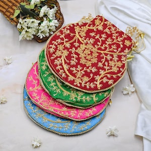 May include: A stack of four embroidered pouches in red, green, pink, and blue. Each pouch features gold floral embroidery and a gold beaded trim. The pouches are arranged in a fan shape, with a white background and floral accents.