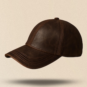 May include: A brown leather baseball cap with a curved brim. The cap has a classic six-panel design with visible stitching and a small button on top. The hat appears to be made of a distressed leather material.