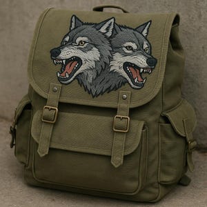 以下が含まれることがあります： 2匹のオオカミが刺繍された、オリーブグリーンのキャンバスバックパック。 バックパックは、2つのバックルストラップ、2つのサイドポケット、上部のハンドルが付いたフラップクロージャーを備えています。 オオカミのデザインは、グレー、白、茶色の色合いです。