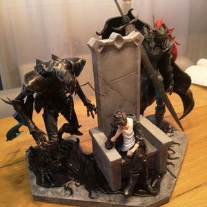 May include: A detailed figurine depicting a fantasy scene with three figures. The central figure sits on a stone throne, flanked by two armored characters. The base measures approximately 11.8 inches in length.