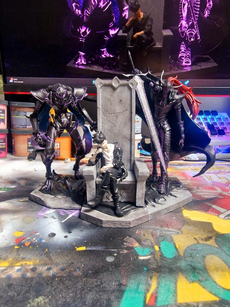 May include: A detailed fantasy figurine set featuring a central figure seated on a throne, flanked by two armored figures. The figures are dark with purple accents, and the throne is gray. The background includes a computer monitor and a colorful surface.