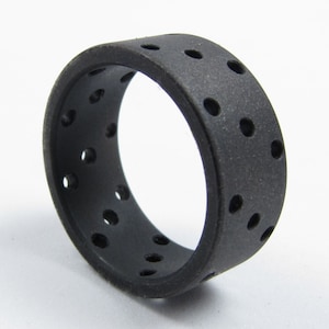 May include: A black rubber ring with a textured surface and multiple small holes.