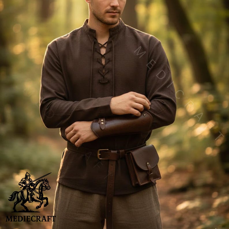 May include: A brown medieval-style shirt with a lace-up neckline and long sleeves. The outfit includes a brown leather belt, a pouch, and arm bracers. The image features the "MEDIECRAFT" logo with a knight on a horse.
