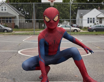 Könnte beinhalten: Ein Ganzkörper-Spider-Man-Kostüm in Rot und Blau mit einer strukturierten Wabenoptik. Der Anzug enthält eine passende Maske mit großen weißen Augenlinsen und einem schwarzen Spinnenemblem, das mittig auf dem Brustbereich platziert ist.