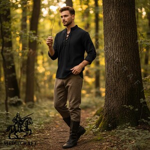 May include: A black long-sleeved shirt with a lace-up neckline and brown trousers. The outfit is completed with black boots. The image is set in a forest with a medieval theme.