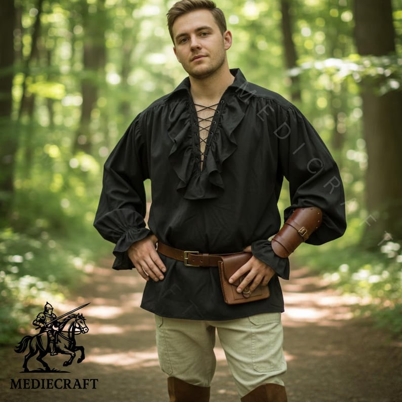 May include: Black long-sleeve shirt with a ruffled front and lace-up detail. The shirt is paired with a brown belt, pouch, and arm guard. The image also shows tan pants and brown boots. The Mediecraft logo is in the bottom left corner.