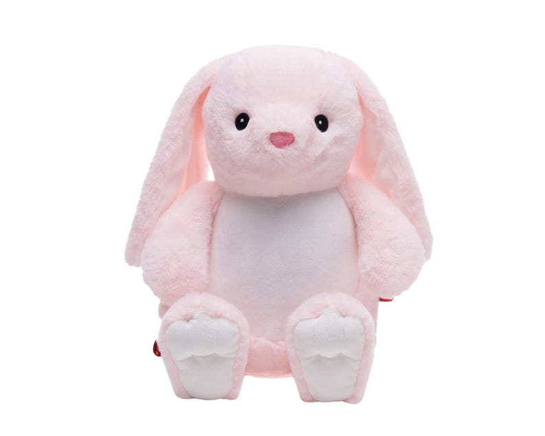 A pink stuffed bunny toy is sitting on a white background.