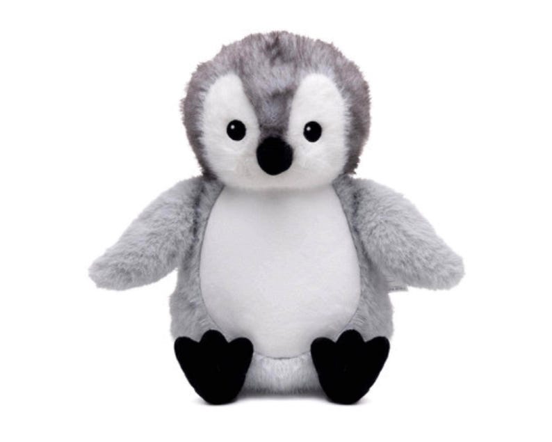 A stuffed penguin toy with a gray and white body and black feet is sitting on a white background.