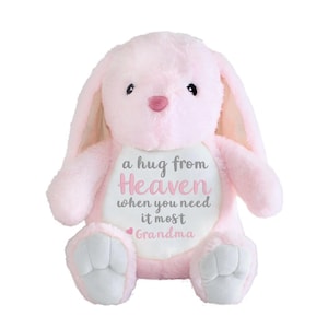 May include: A plush pink bunny with long ears and a white belly patch. The patch features the text "a hug from Heaven when you need it most Grandma" in gray and pink script. The bunny has gray paw pads and a pink nose.