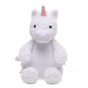 A white plush unicorn toy with a pink horn and tail sits against a white background.