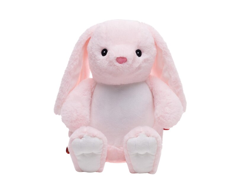A pink stuffed bunny toy is sitting on a white background.