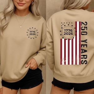 May include: A tan sweatshirt with a crew neck. The front features a circular design with the text "1776 2026" surrounded by stars. The back displays a distressed American flag design with the text "250 YEARS".