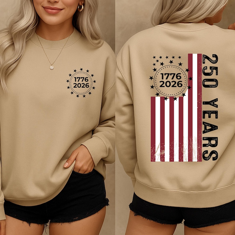 May include: A tan sweatshirt with a crew neck. The front features a circular design with the text "1776 2026" surrounded by stars. The back displays a distressed American flag design with the text "250 YEARS".