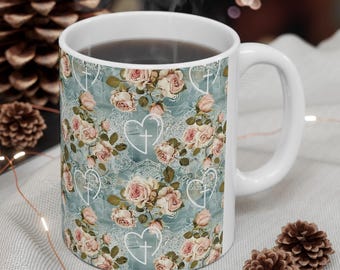 May include: A white ceramic mug with a blue and white floral pattern. The pattern includes roses, hearts, and crosses. The mug is filled with coffee or tea.