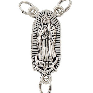 May include: A silver-toned keychain with a detailed depiction of the Virgin Mary. The religious pendant has a rectangular shape with a halo and is attached to multiple key rings.