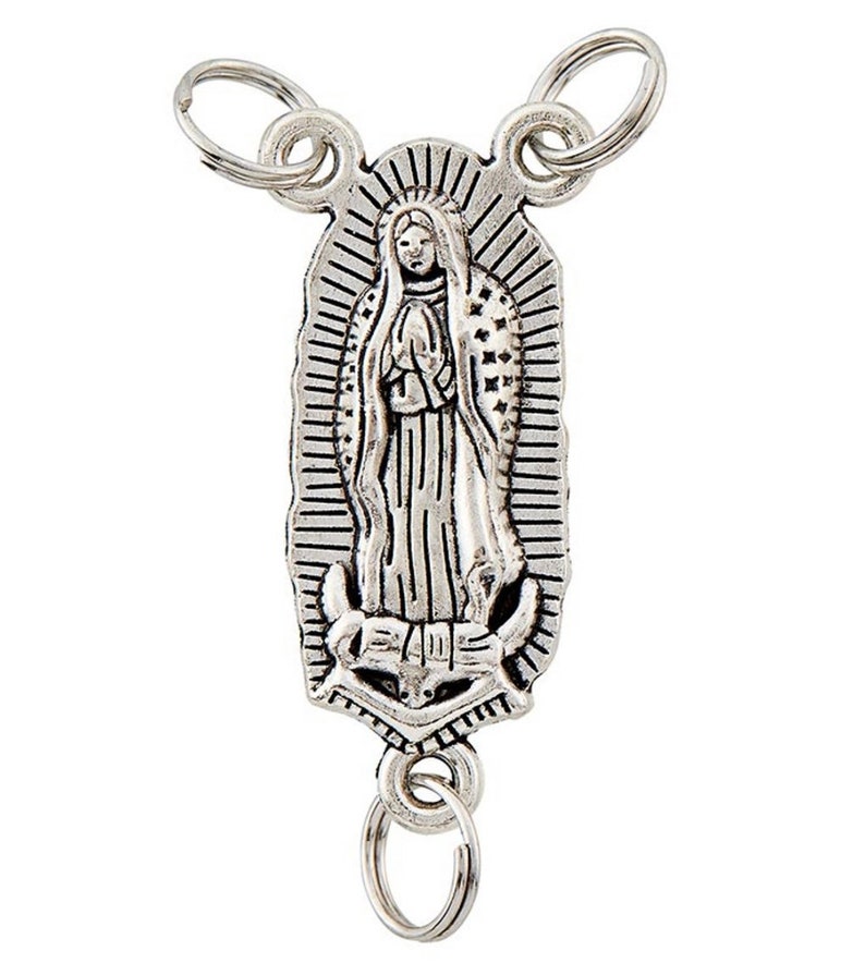 May include: A silver-toned keychain with a detailed depiction of the Virgin Mary. The religious pendant has a rectangular shape with a halo and is attached to multiple key rings.