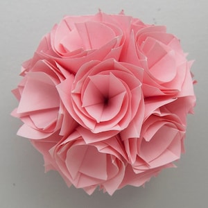 May include: A pink origami flower sphere made of folded paper. The sphere is made up of several individual flowers, each with a layered, folded design.