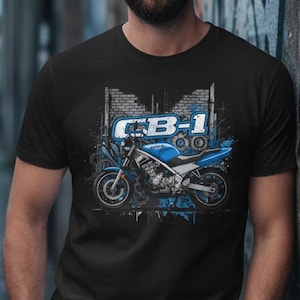 Könnte beinhalten: Schwarzes T-Shirt mit einer blauen Motorradgrafik und dem Text "CB-1". Das Motorraddesign hat blaue Details. Das T-Shirt besteht aus einem dunklen Stoff.