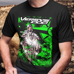 Könnte beinhalten: Schwarzes T-Shirt mit einem Motorrad-Motiv und dem Text "VERSYS 1000" in Weiß und Grün. Das Design zeigt einen Fahrer auf einem Motorrad mit grünen Farbspritzern.