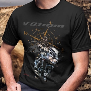 Op de afbeelding: Zwart t-shirt met een motorfietsafbeelding, de tekst "V-Strom" en een kompasontwerp. De afbeelding toont een rijder op een motorfiets. Het shirt is zwart.