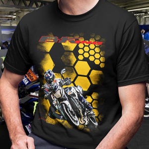 May include: Black t-shirt featuring a motorcycle graphic with the text "BR". The design includes a yellow honeycomb pattern and a motorcycle racing image. The shirt is a classic crew neck.