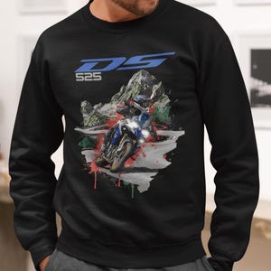 May include: Black sweatshirt featuring a motorcycle graphic with the text "DS 525" in blue. The design includes a motorcycle racing on a mountain road with red, green, and white paint splatter.
