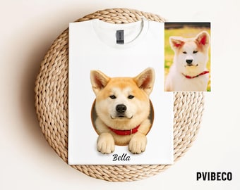 May include: White t-shirt featuring a portrait of an Akita dog with a red collar, emerging from a circular frame. The dog's name, "Bella," is printed below. A smaller image of the dog is in the upper right corner. The brand name "PVIBECO" is printed at the bottom.